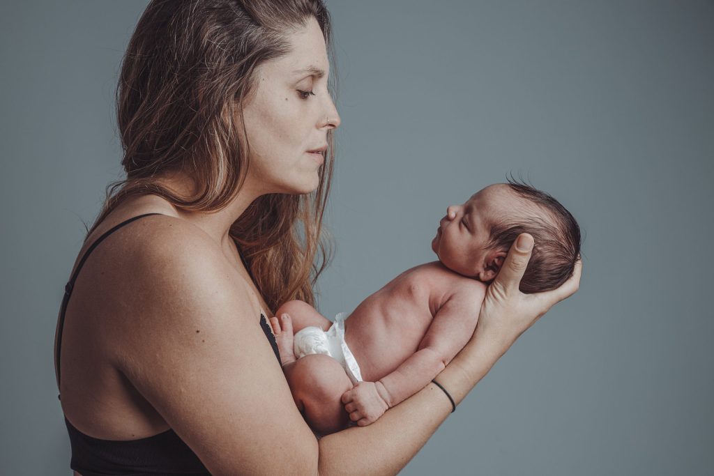 Mother holds her newborn son with loving expression