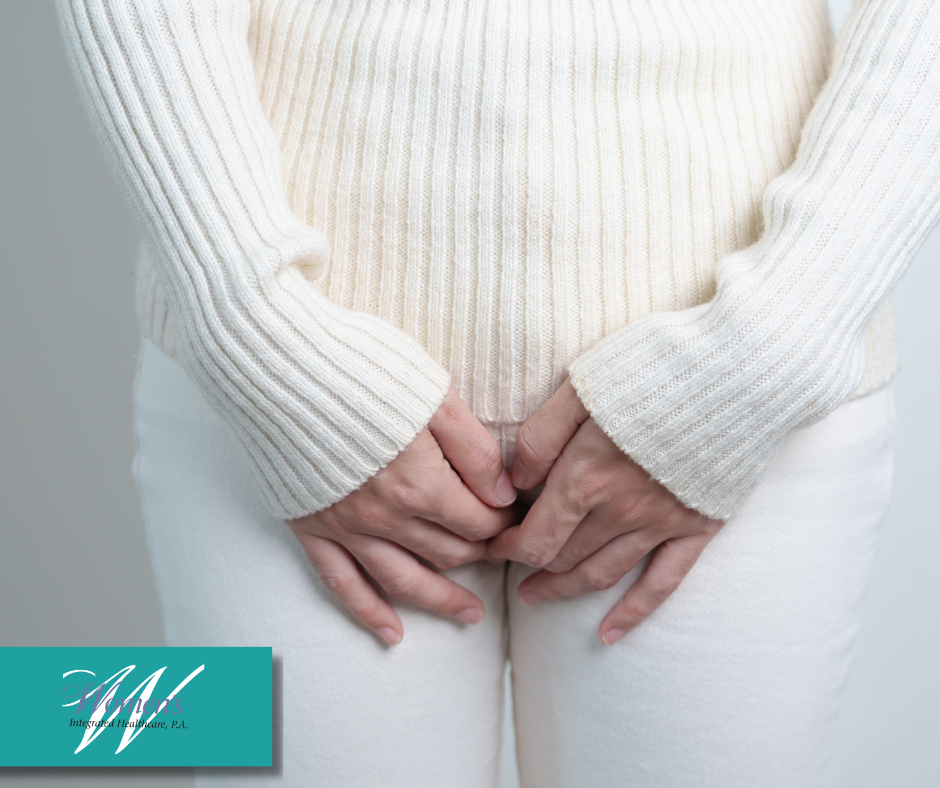 Close up of a woman's hands holding her middle section like she needs to pee.
