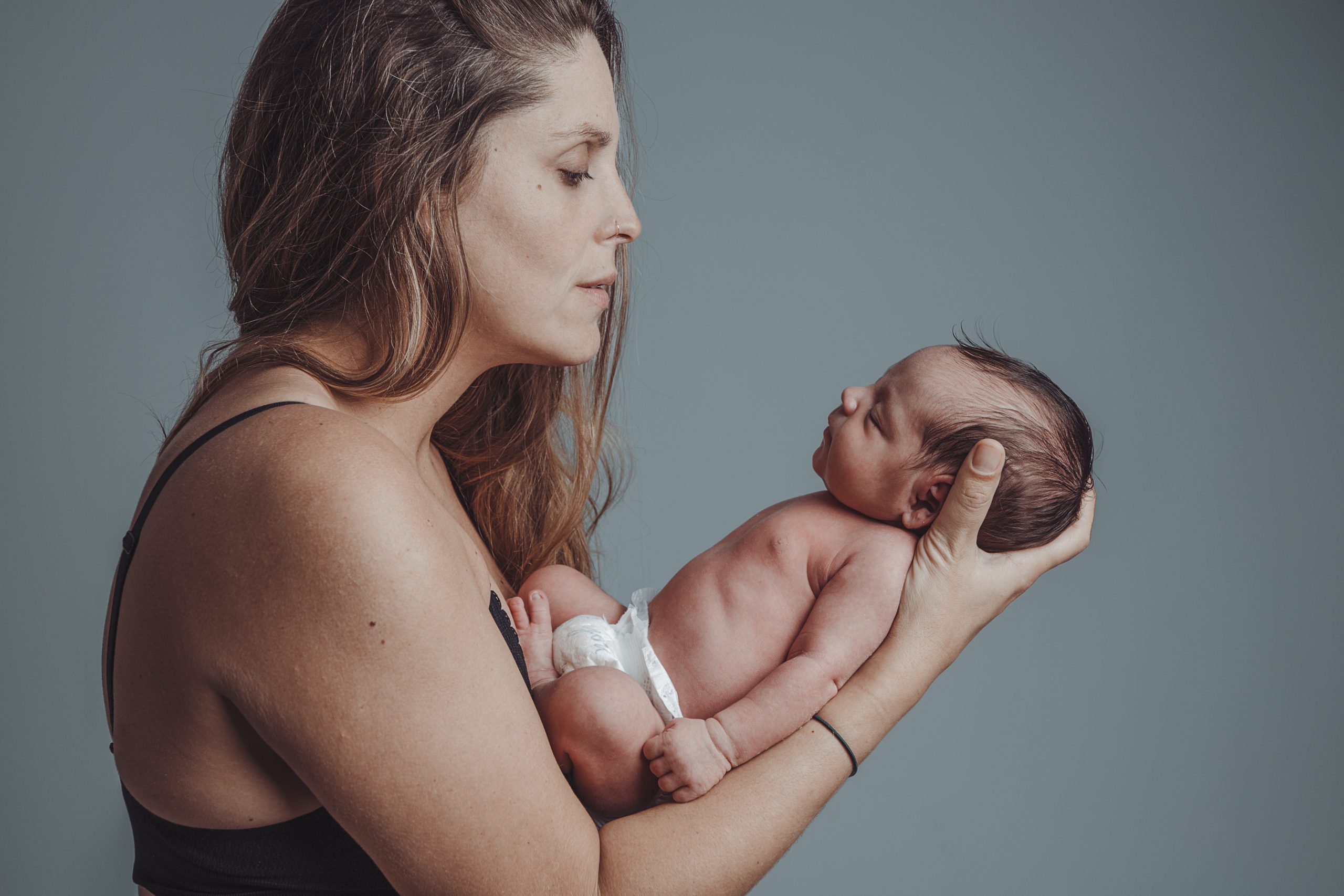 Mother holds her newborn son with loving expression