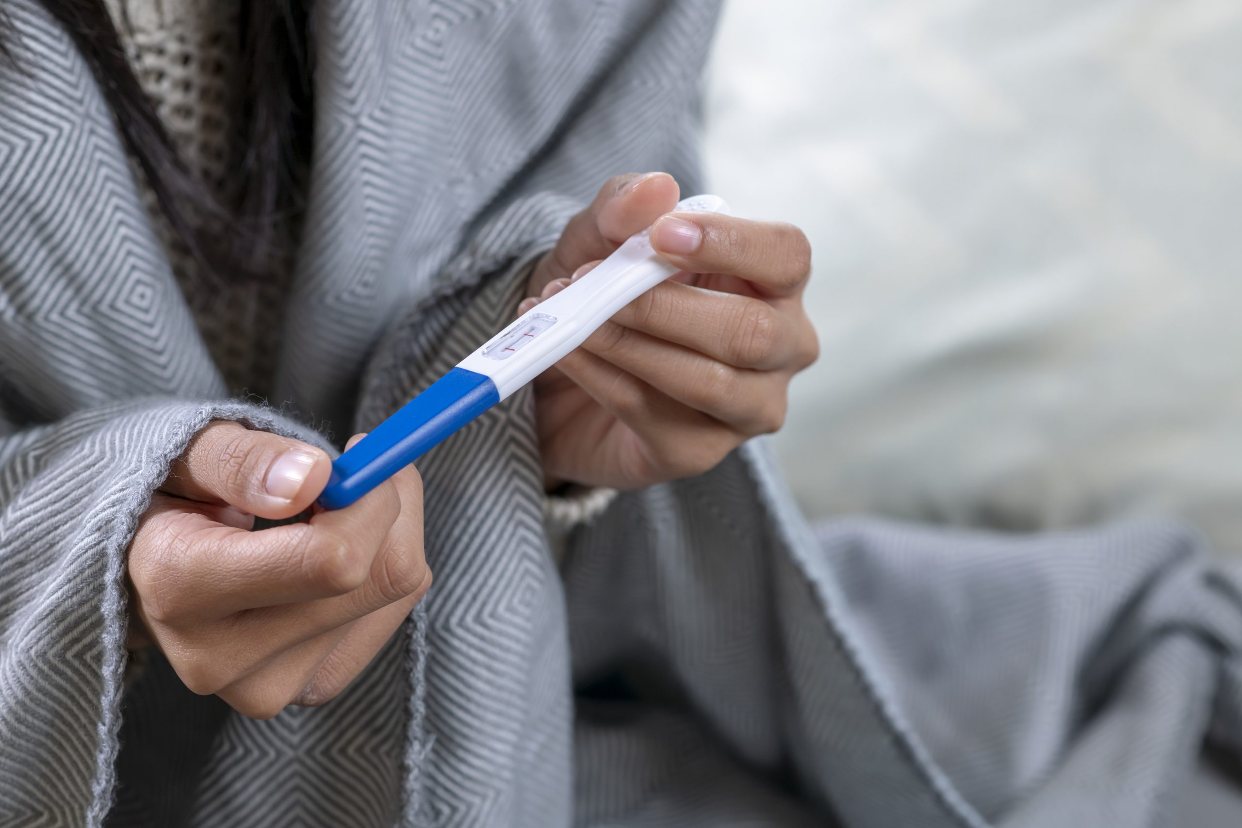 Young woman with pregnancy test in bedroom, closeup