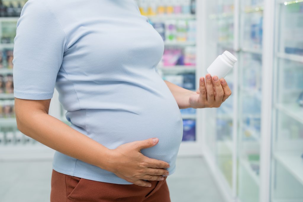 Pregnant woman reading a medicine bottle.
