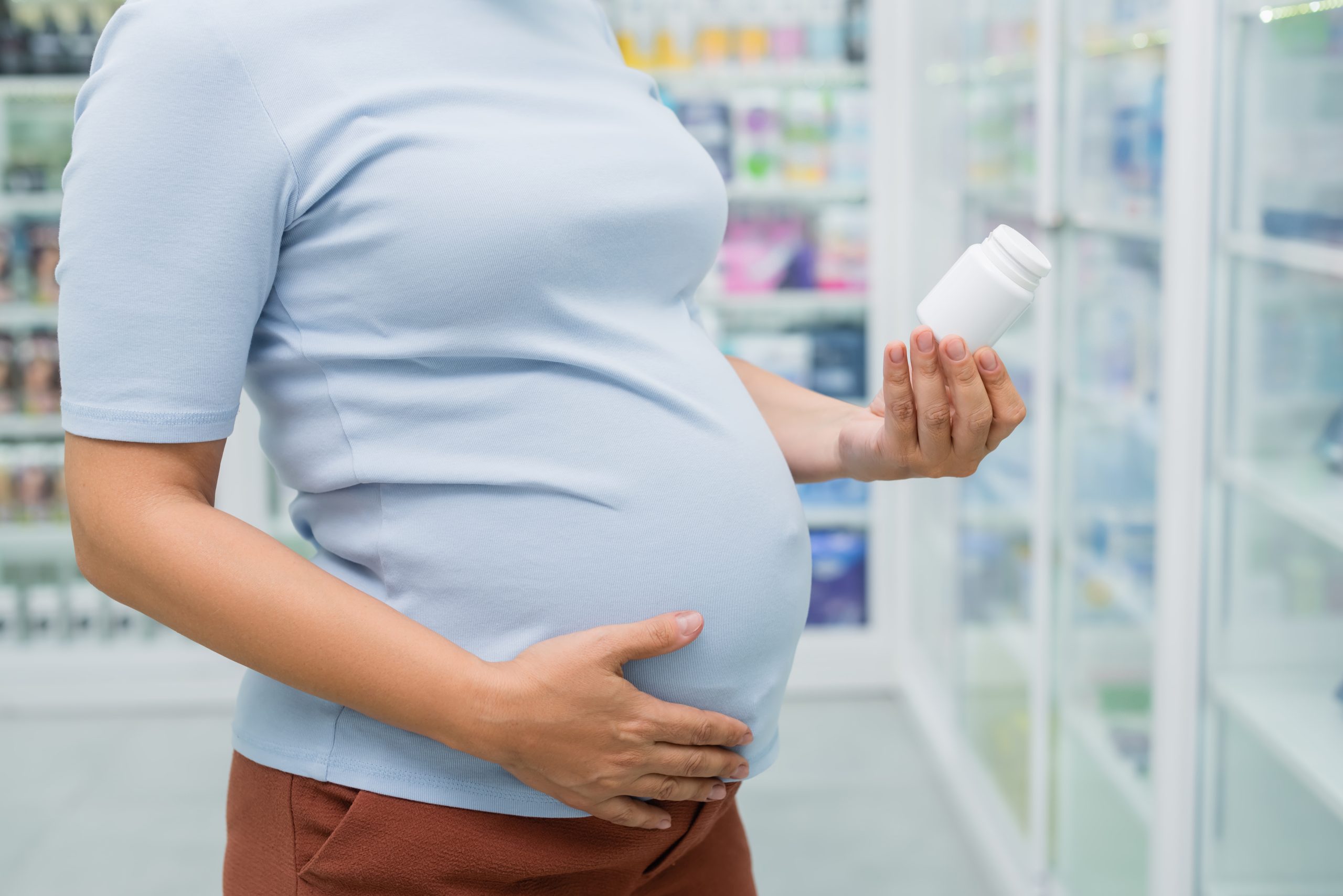Pregnant woman reading a medicine bottle.