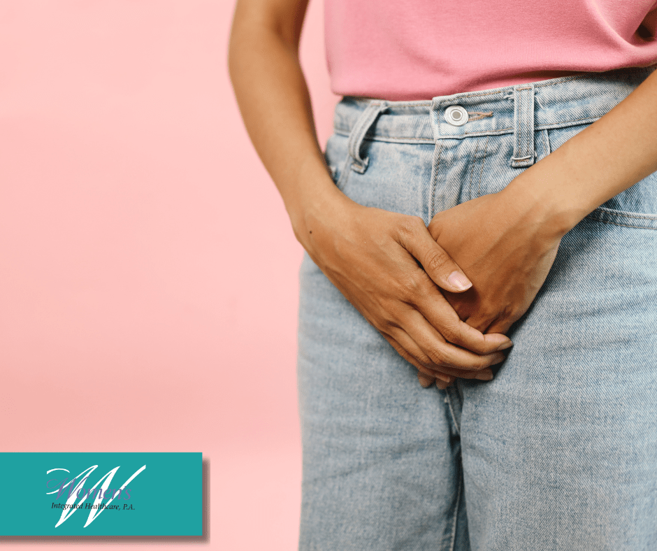Close up of a woman in jeans holding her hands over her pubic area to illustrate discomfort.